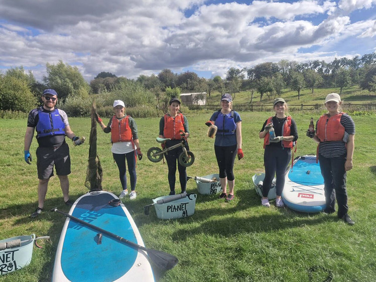 people standing in a green space with paddleboards