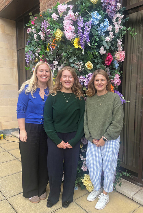 Three Women in front of flowers