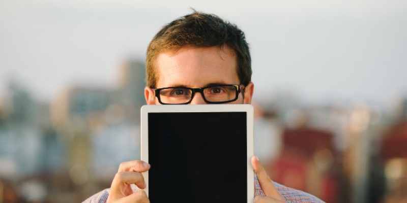 A man holding a tablet device in front of his face