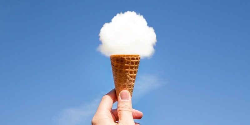 Hand holding a ice cream cone with one scoop of cloud in it