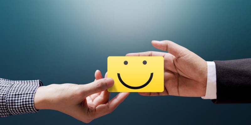 Hand giving a card with a smiley face to another hand
